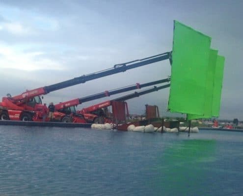 Mobile cranes carrying green screens on movie set