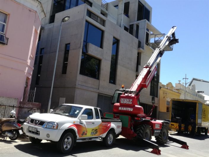 Mobile crane lifting furniture from the street