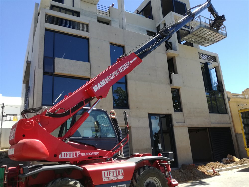 Mobile crane lifting furniture to apartment